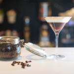 Espresso martini with jar of coffee beans next to it