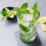 Mojito cocktail with lime and mint in highball glass on a grey stone background