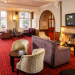 Cosy armchairs, two glasses of red wine next to a roaring fire in the lounge at Mercure Leeds Parkway Hotel