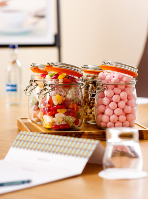 Mercure-branded notepaper in a meeting room, with sweets in a jar and bottles of water blurred in the background