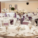 The Park Side Room at Mercure Leeds Parkway Hotel set up for a wedding breakfast, purple sashes, white tablecloths and purple flowers