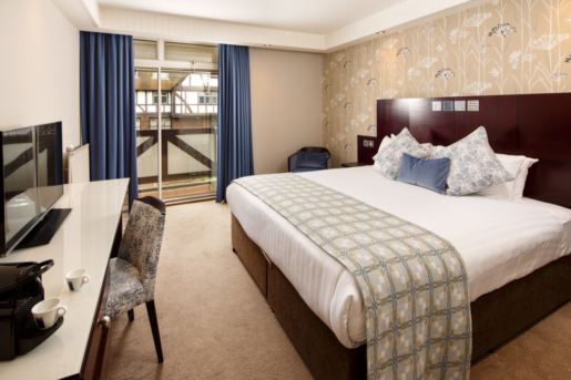 Privilege bedroom at Mercure Leeds Parkway Hotel, blue velvet cushion on bed, blue floor length curtain and white desk