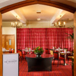 The Brasserie restaurant at Mercure Leeds Parkway Hotel, red curtains, carpet and dark wooden furniture