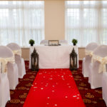 The Senate Room at Mercure Leeds Parkway Hotel set up for a wedding ceremony, with red carpet aisle and white chairs