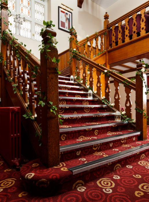 The staircase in the lobby at Mercure Leeds Parkway Hotel dressed for a wedding with ivy and tea light holders